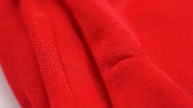 Close up of red fabric with frayed thread and textile texture detail.