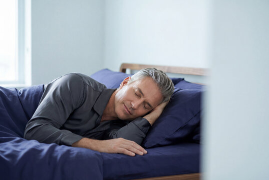 Peaceful middle aged man with glowing skin sleeping soundly in a bed