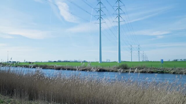 Dutch polder landscape with electricity pylons and canal