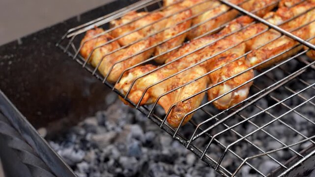 BBQ picnic time Roasted chicken legs and wings on grill. Grilling meat on outdoor grill grid tasty barbeque chicken steak with smoke flames juicy meat in the backyard in summer
