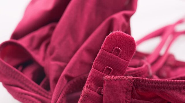 Close up of sports bra hook and strap detail on red fabric.
