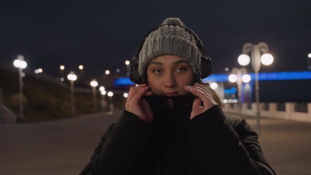Dancer enjoys city illuminated surroundings. Performer in evening observes silent cityscape glow. Performing artist in evening attire gazes at tranquil glowing city skyline at night