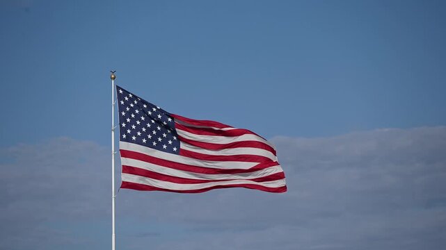 American Flag Waving in Wind Against Clear Blue Sky with Copy Space