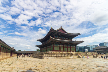 Fototapeta premium Majestic Korean palace architecture with symmetrical stone courtyard and layered tiled roof under dramatic sky, traditional Asian heritage landmark, cultural travel destination concept