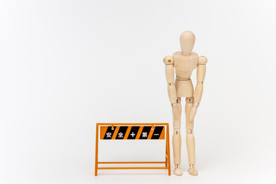 工事現場のバリケードの横でお辞儀する人形