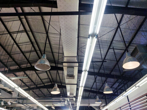 Brilliant industrial ceiling within a large big-box store features twin fluorescent tube fixtures, suspended ventilation ducts, and a complex steel framework with reflective insulation.
