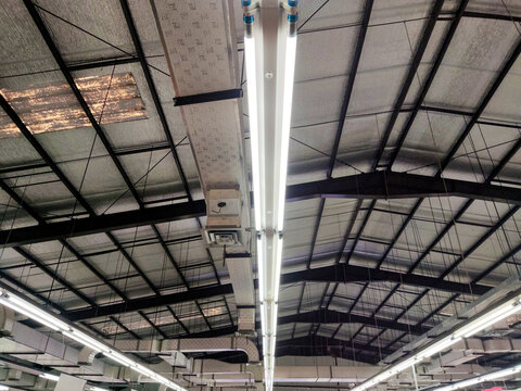 Brilliant industrial ceiling within a large big-box store features twin fluorescent tube fixtures, suspended ventilation ducts, and a complex steel framework with reflective insulation.