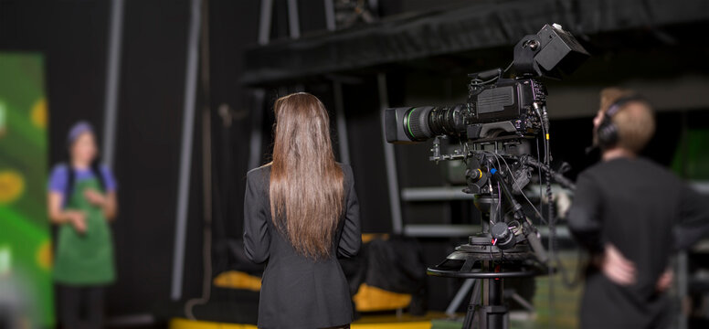 Professional broadcast camera filming female talk show host in modern news studio with copy space