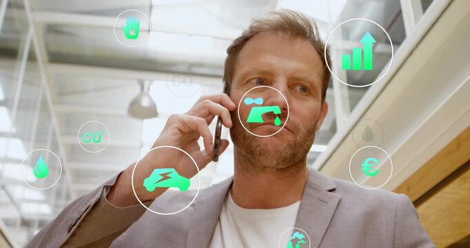 Receiving call, man walking atrium on phone, icons orbiting faucet, car, chart, discussing business