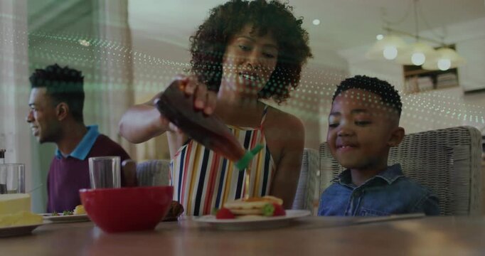Food content woman pouring syrup onto pancakes, picking up bottle and guiding stream for family
