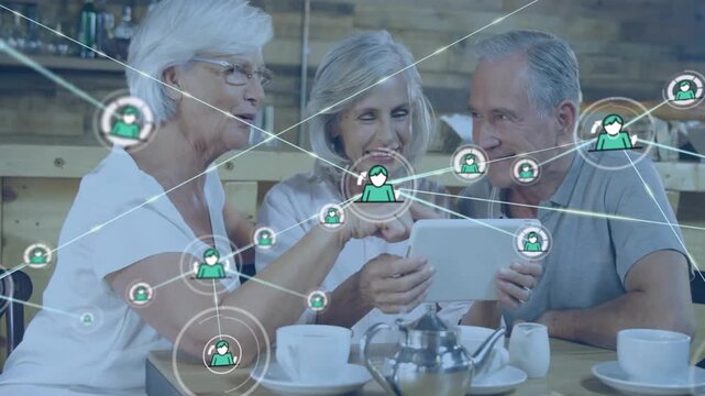 Three seniors pointing and tapping tablet in cafe, showing social web with green user icons growing