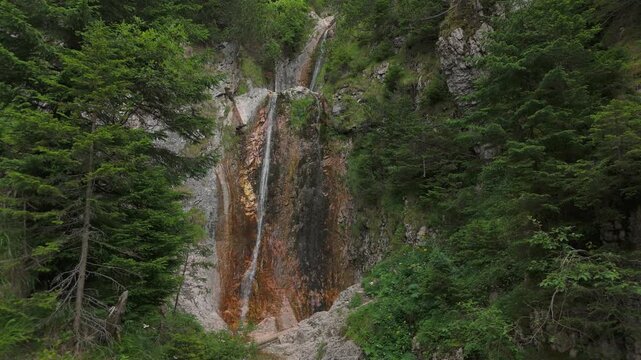 Serene Moara Dracului waterfall hidden in lush green Gaura valley within the majestic Bucegi Mountains, a static cinematic shot of wild nature in Romania