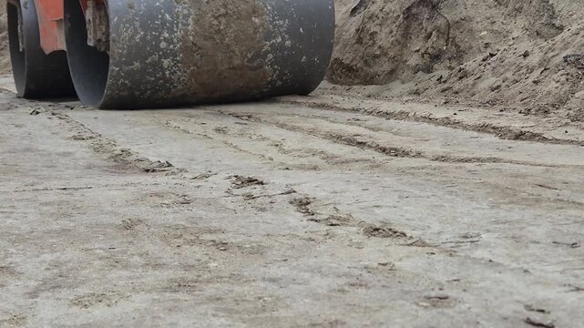 Side view of a heavy road roller approaching from a distance and passing by at a slight angle.