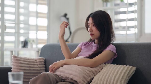 Asian adult woman sitting sofa home deep thought contemplating hand personal wellness mental wellbeing quiet moment introspection