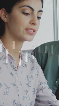 Woman speaking and bringing smartphone into view, showing data to colleague in business meeting