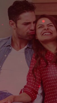 Lifting phone couple red-blouse, denim taking selfie at home then reviewing for fun with red filter