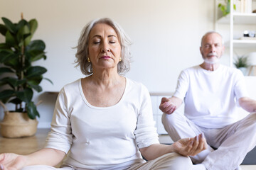 Obraz premium Senior couple practicing yoga and meditation at home for wellbeing