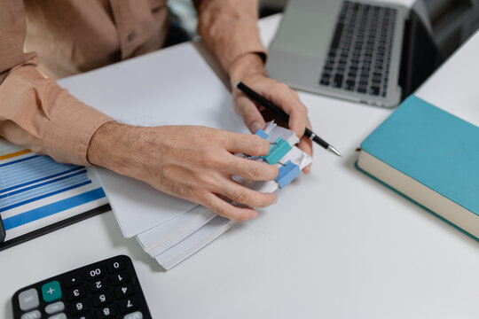 Close up of person organizing financial documents with clips on desk, representing paperwork management, accounting process, office organization, and financial record keeping.