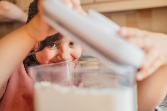 Child opening flour container in kitchen, home cooking process.