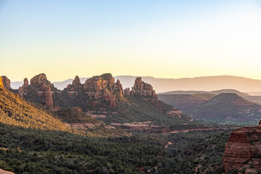 Jagged rock formations and forested landscape at sunset