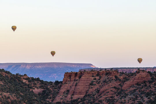 Hot air balloons over red rock mesa landscape sunrise