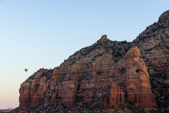 Jagged rock formation and distant hot air balloon sunrise