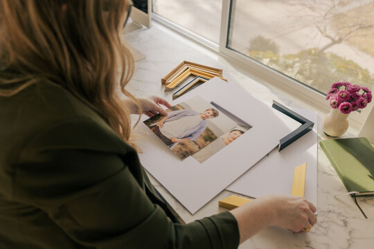 Person arranging framed portraits on desk
