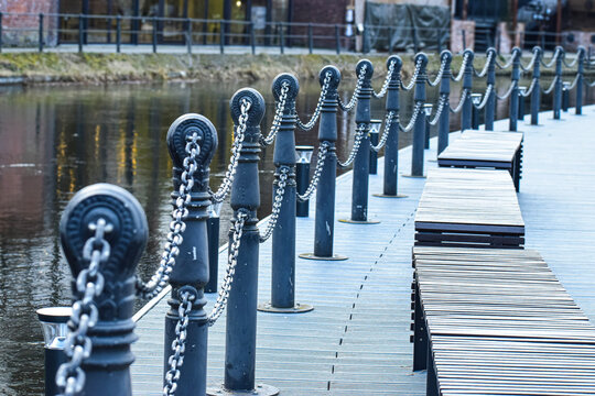 Waterfront promenade with decorative chain barriers and modern wooden benches