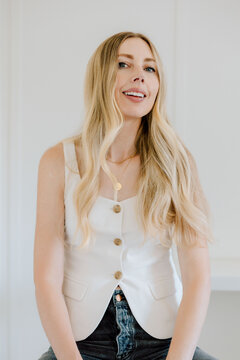 Stylish woman with long blonde hair sitting indoors