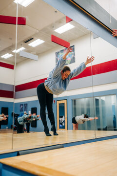 Woman stretching in dance studio with reflection