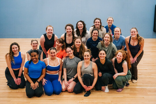 Group of women posing and smiling after fitness class in studio