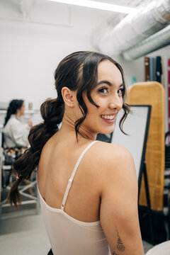 Happy woman smiling looking back in a white workshop