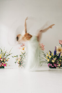 Woman dancing among flowers with ethereal motion blur