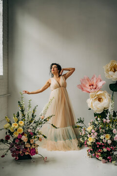 Woman in ethereal gown surrounded by spring flower arrangements