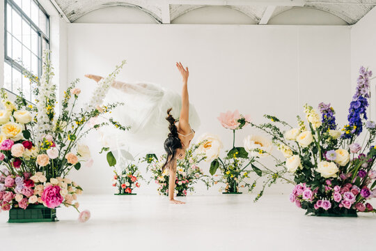 Ballet dancer in handstand among vibrant floral arrangements