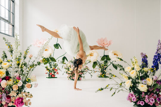 Female dancer performing handstand in floral studio