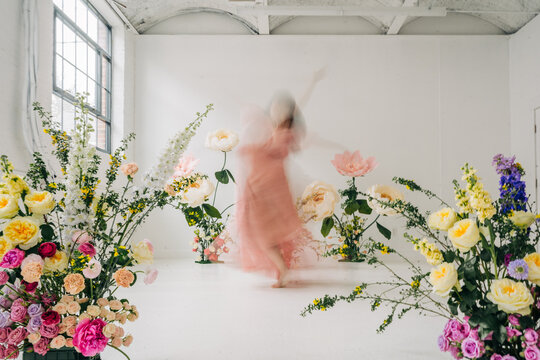 Dancer moving in blurred pink dress among flowers