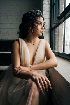 Woman in evening gown contemplating view through window