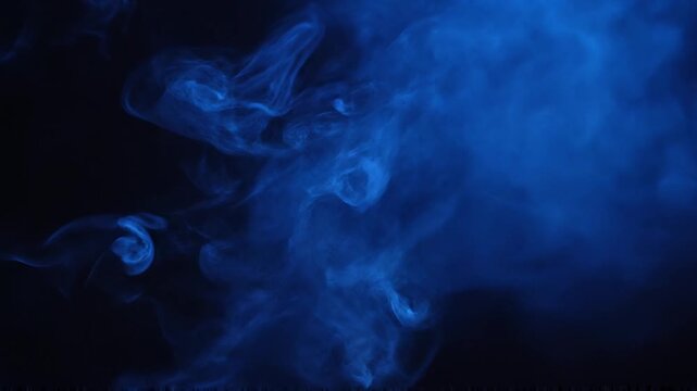 Blue smoke swirls in darkness creating mysterious shapes and forms