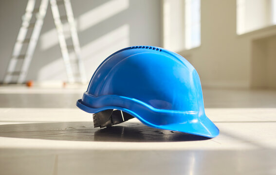 Hardhat helmet for safety and construction protection. Blue helmet on a bright floor, suggesting renovation, engineering and site compliance. Clear message of safety equipment and workwear.