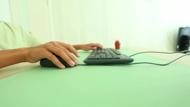 Side angle view of hands typing and using a mouse on a mint green desk mat, subtle cactus in background, highlighting focused digital work, ergonomic setup, and calm, intentional productivity.