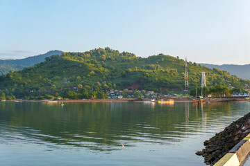 Obraz premium Serene water reflects lush green hills and distant town