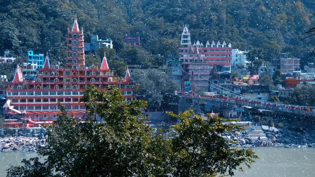 Scenic view of the Trayambakeshwar Temple (the Tera Manzil Temple) and the Lakshman Jhula bridge across the holy river Ganga (Ganges) in Rishikesh, Uttarakhand, India. View through sparkling particles