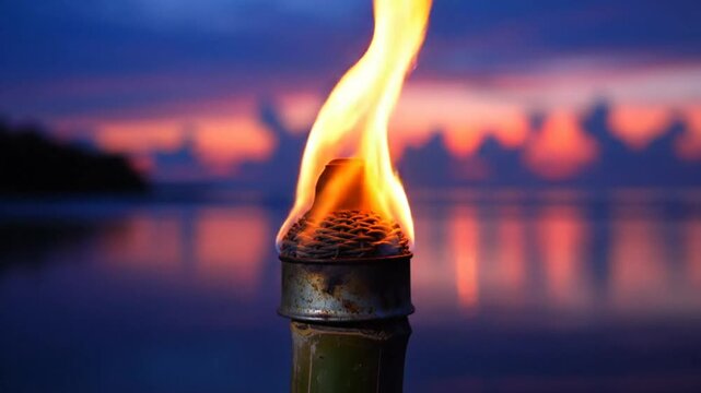 Burning torch lit with orange flames reflecting in tranquil ocean waters during a vibrant sunset