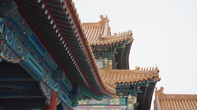 Ornate golden rooflines and eaves, cinematic closeup of painted brackets and tiled ridge, photographer framing symmetry and texture, soft overcast light, tranquil heritage mood, imperial palace