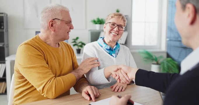Seniors couple handshake with advisor during consultation. The clients hold a meeting to finalize an agreement and review retirement planning and investments. Concept shows trust and contract.