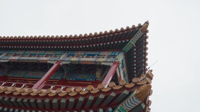 Corner temple roof with red pillars, intricate bracketwork and painted beams, sweeping upward angle captures dynamic cultural energy, ideal for travel films, drone sequences, and architectural study.