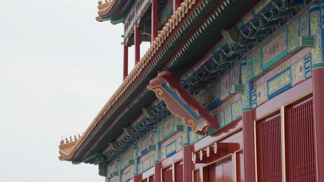 Painted temple beams and red doors, closeup of colorful facade with lacquered panels and carved brackets, soft overcast light accentuates texture and pattern, mood intimate and artistic for editorial