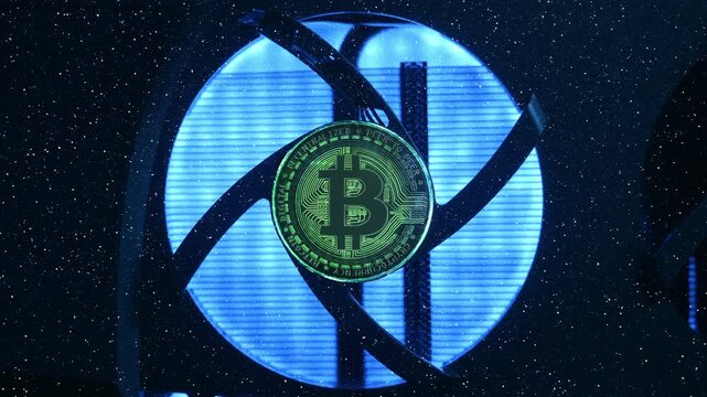 Cooling fan is spinning on the video card, Bitcoin coin is shine in the light as a symbol of cryptocurrency mining using computer video cards. Macro. Closeup. In work video adapter (graphics adapter)
