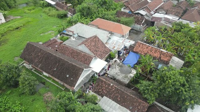 Aerial 4K view of people gathering for a traditional ceremony in an Indonesian neighborhood.